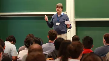 Felix Otto addressing a crowd of young mathematicians in front of a blackboard