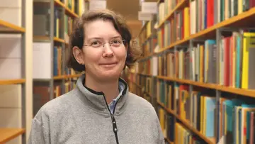 Portrait of Angkana Rüland in front of a bookshelf