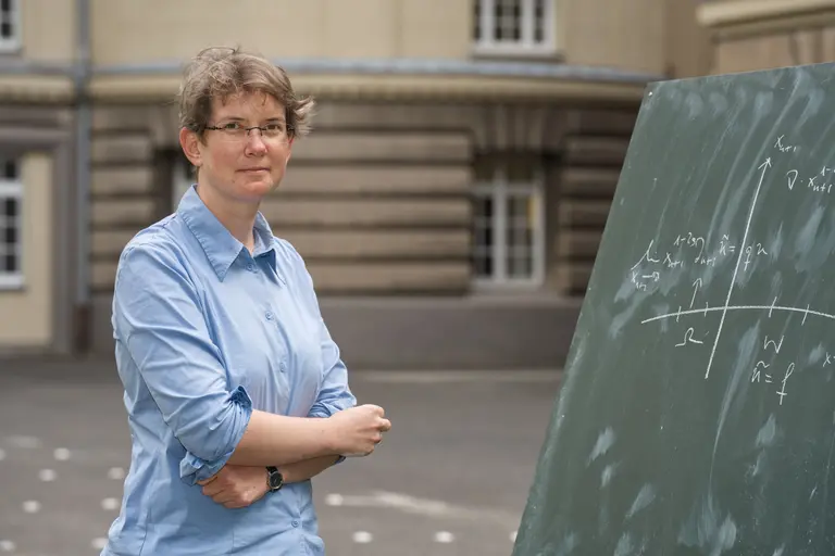 Angkana Rüland outdoors next to a blackboard featuring a coordinate system