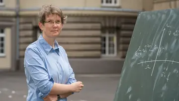 Angkana Rüland outdoors next to a blackboard featuring a coordinate system