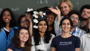 Nidhi Kaihnsa in the middle of a group of scientists. She is wearing a doctoral hat.
