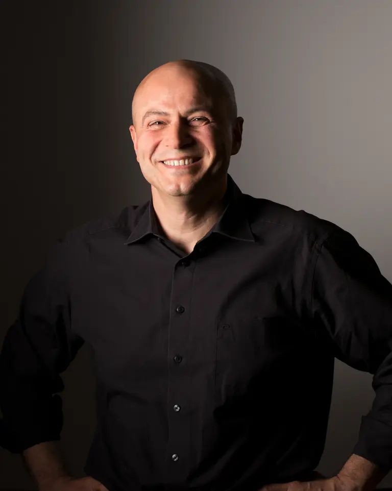 Portrait of Nihat Ay in front of a black and gray background