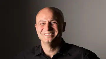 Portrait of Nihat Ay in front of a black and gray background