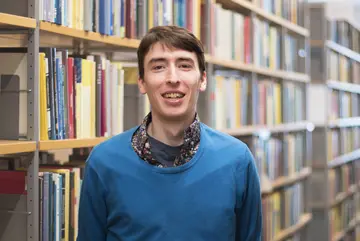 Portrait of Sam G. Krupa in front of bookshelves