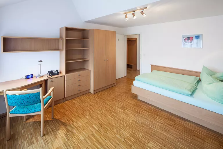 A bedroom with bed, desk and empty cabinets