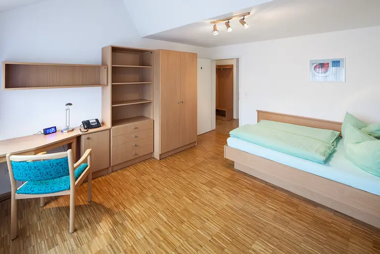 A bedroom with bed, desk and empty cabinets