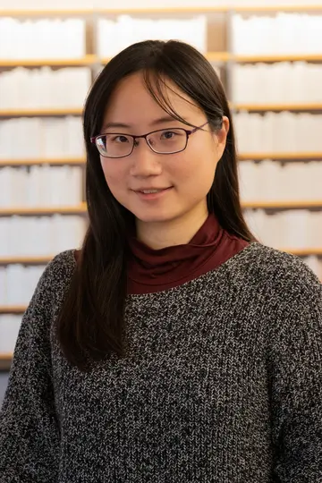 Portrait of Enya Hsiao in front of bookshelves