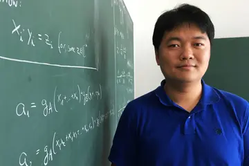Yue Ren next to a blackboard with mathematical formulas