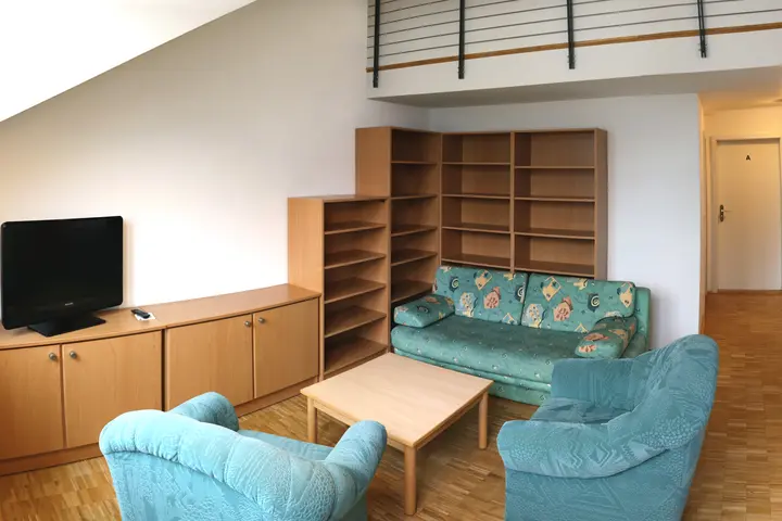 Wohnzimmer mit Sofas, Tisch, Fernseher und Schränken