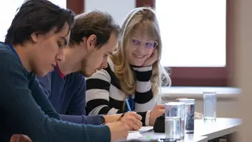 A group of students sitting at a desk and exchanging ideas