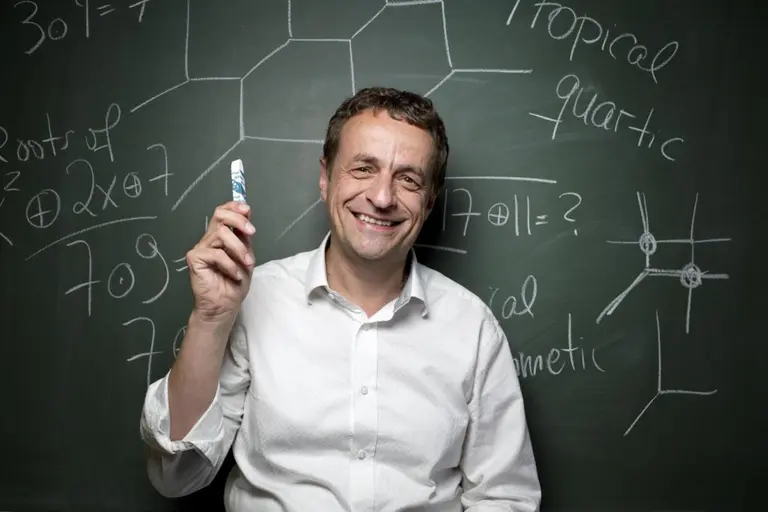 Portrait von Bernd Sturmfels vor einer Tafel mit mathematischen Formeln