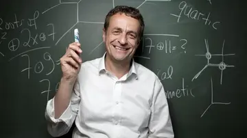 Portrait of Bernd Sturmfels, a blackboard with mathematical formulas in the background