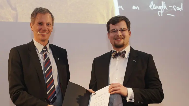 Tobias Ried bei der Preisverleihung, hält eine Urkunde in Händen