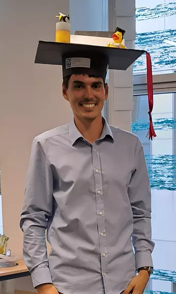 Portrait of Markus Tempelmayr, wearing a big selfmade PhD hat